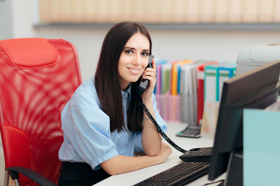 Office staff member answering a phone at a contractor’s office, illustrating the importance of a fast five-minute lead response time.